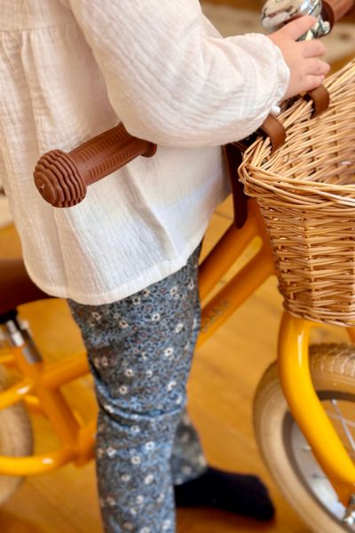 petite fille qui porte le pantalon en coton à fleurs turquoises et la blouse Ava à manches longues en gaze de coton écrue de chez bobine paris