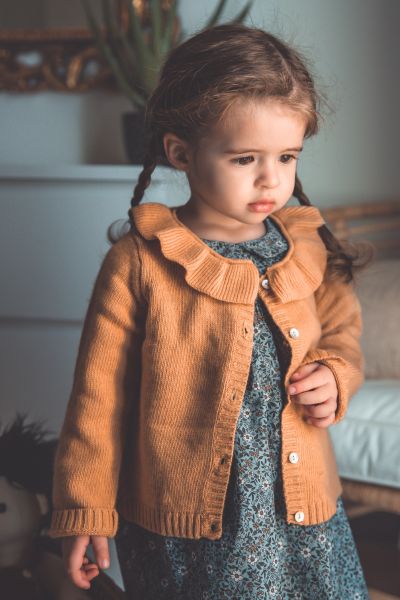 petite fille qui porte une robe en coton turquoise à fleurs et un cardigan en laine et cachemire