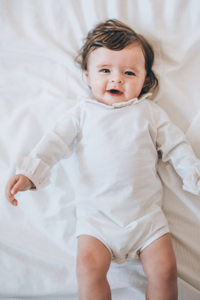Bébé souriant qui porte un body blanc