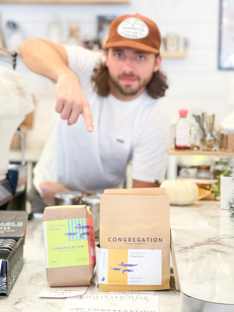 A barista points at some Congregation retail bags