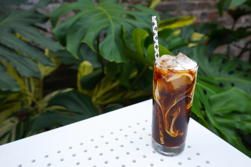 A tall glass of cold brew with cream spiraling in.