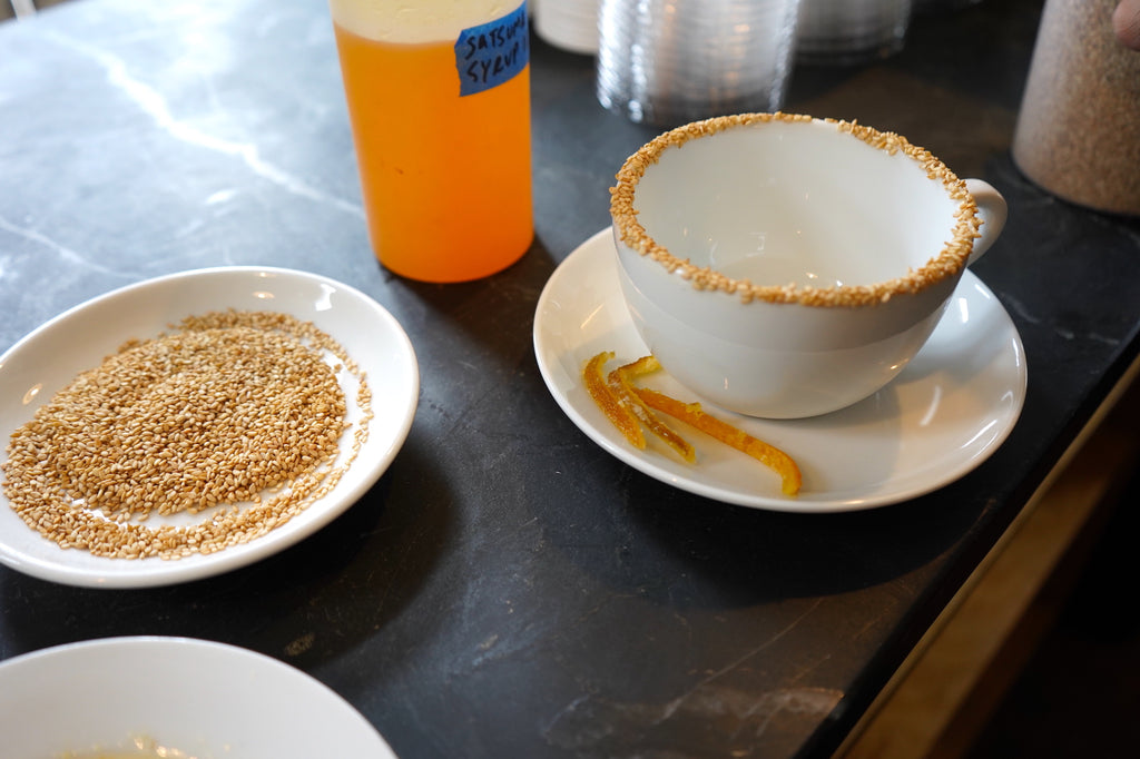 A cafe mug is rimmed with sesame, prepared to hold a Honey I Toasted the Sesame latte