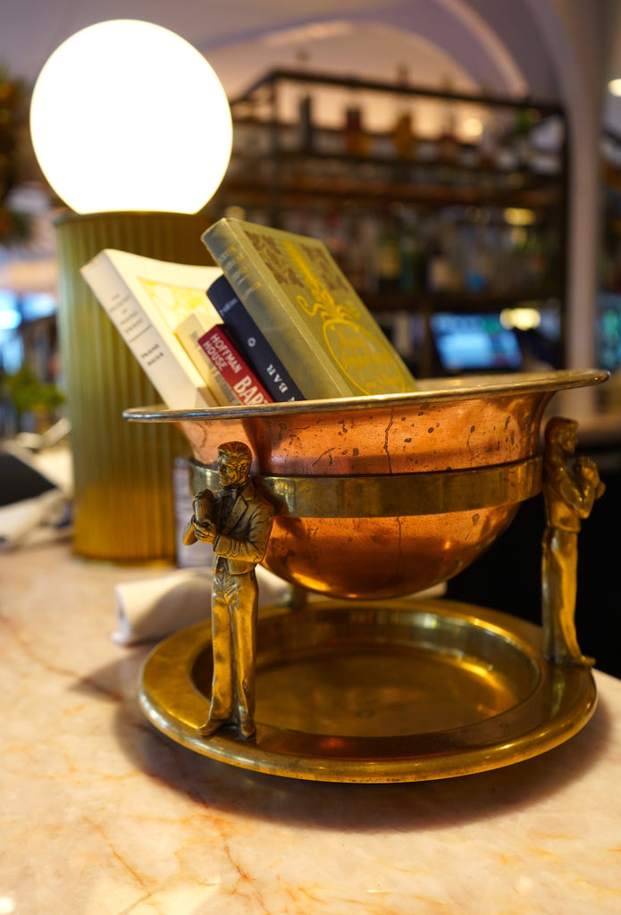 A decorative vessel holding cocktail books