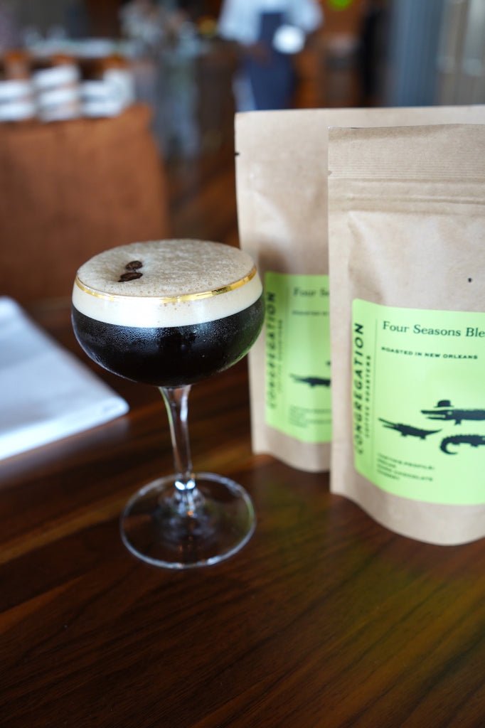 An espresso martini flanked by gift bags of the Four Seasons Blend