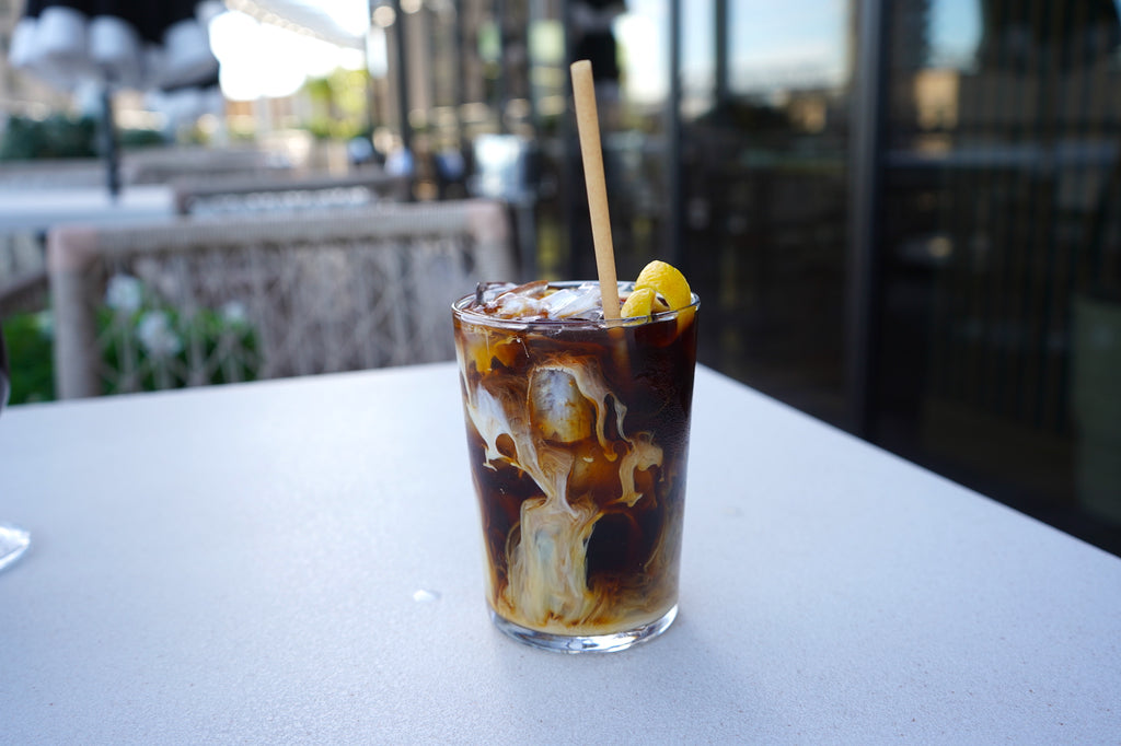 Cream swirls into a cold brew iced coffee on the terrace overlooking the Mississippi River.