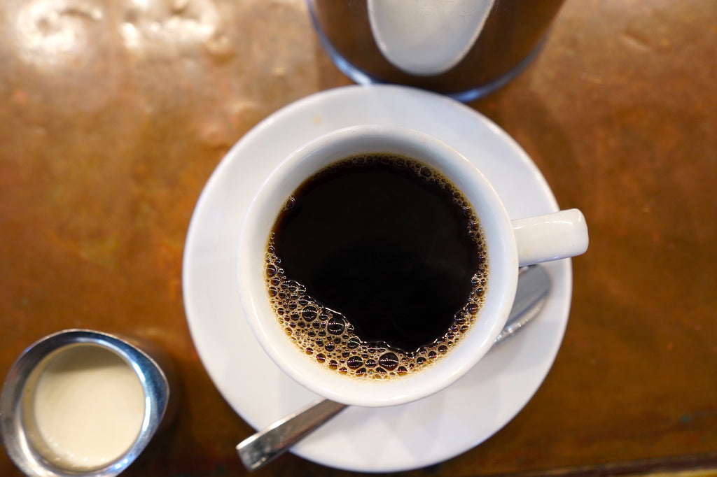 Black coffee in a white mug on a copper bar top