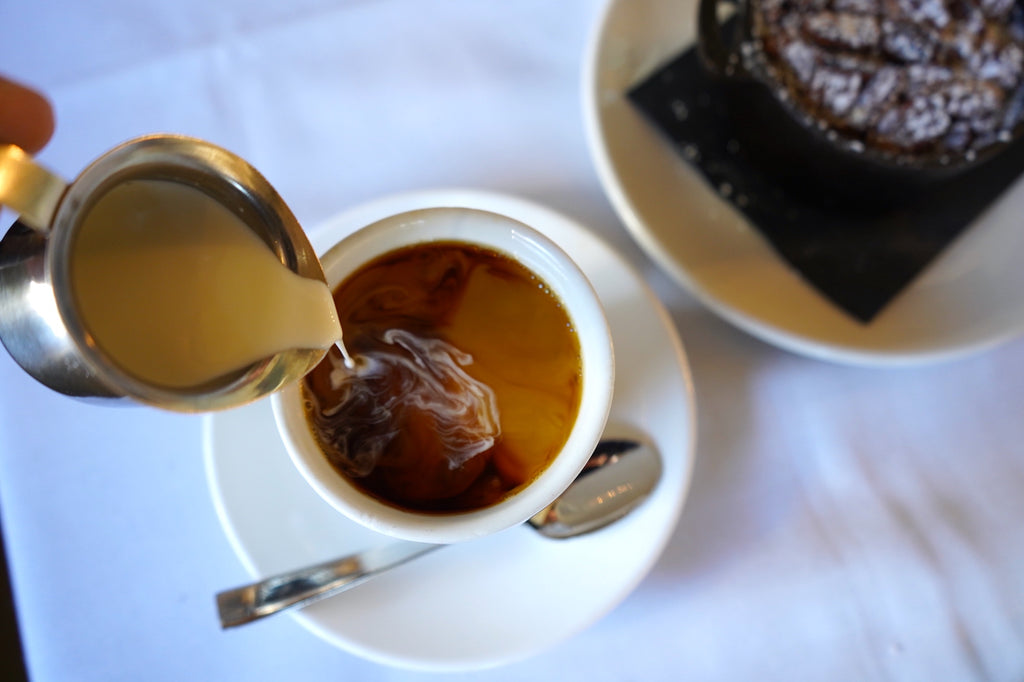 Cream poured into a cup of black coffee