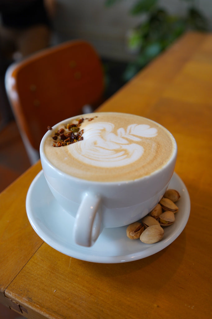 A hot latte with a pistachio crumble