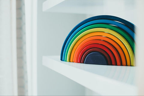 wooden rainbow sitting on a white shelf