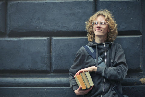 high school boy holding books and carrying a book bag