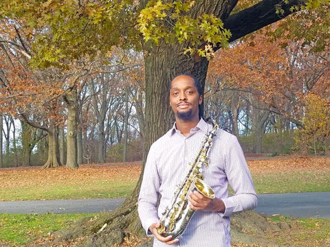 Photo of Carl Bartlett, Jr. outdoors, holding saxophone.  Photo courtesy of Buzz B