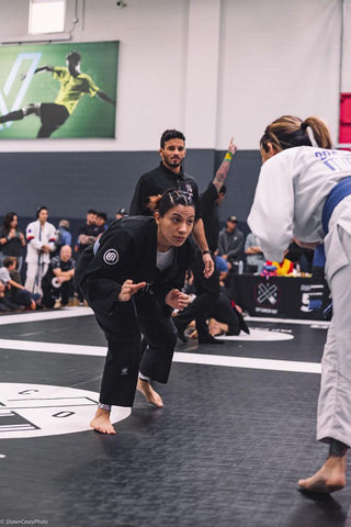 Female BJJ competitor in the middle of a jiu jitsu match