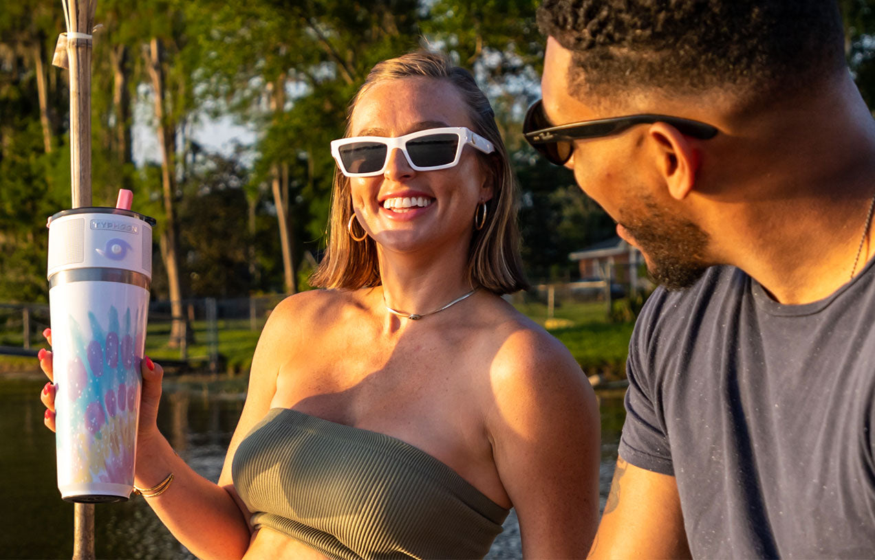 two people having a laugh as one is holding a white typhoone speaker on a iridescent tumble