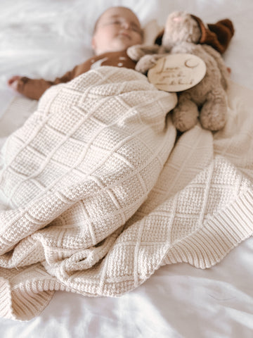 Baby sleeping under a Snuggly Jacks cream organic knitted blanket