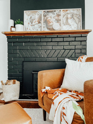 Black fire place with a leather chair in front of it and a snuggly jacks havana organic knitted blanket draped over the chair.