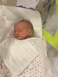 Newborn baby in hospital crib snuggled under a warm minky blanket