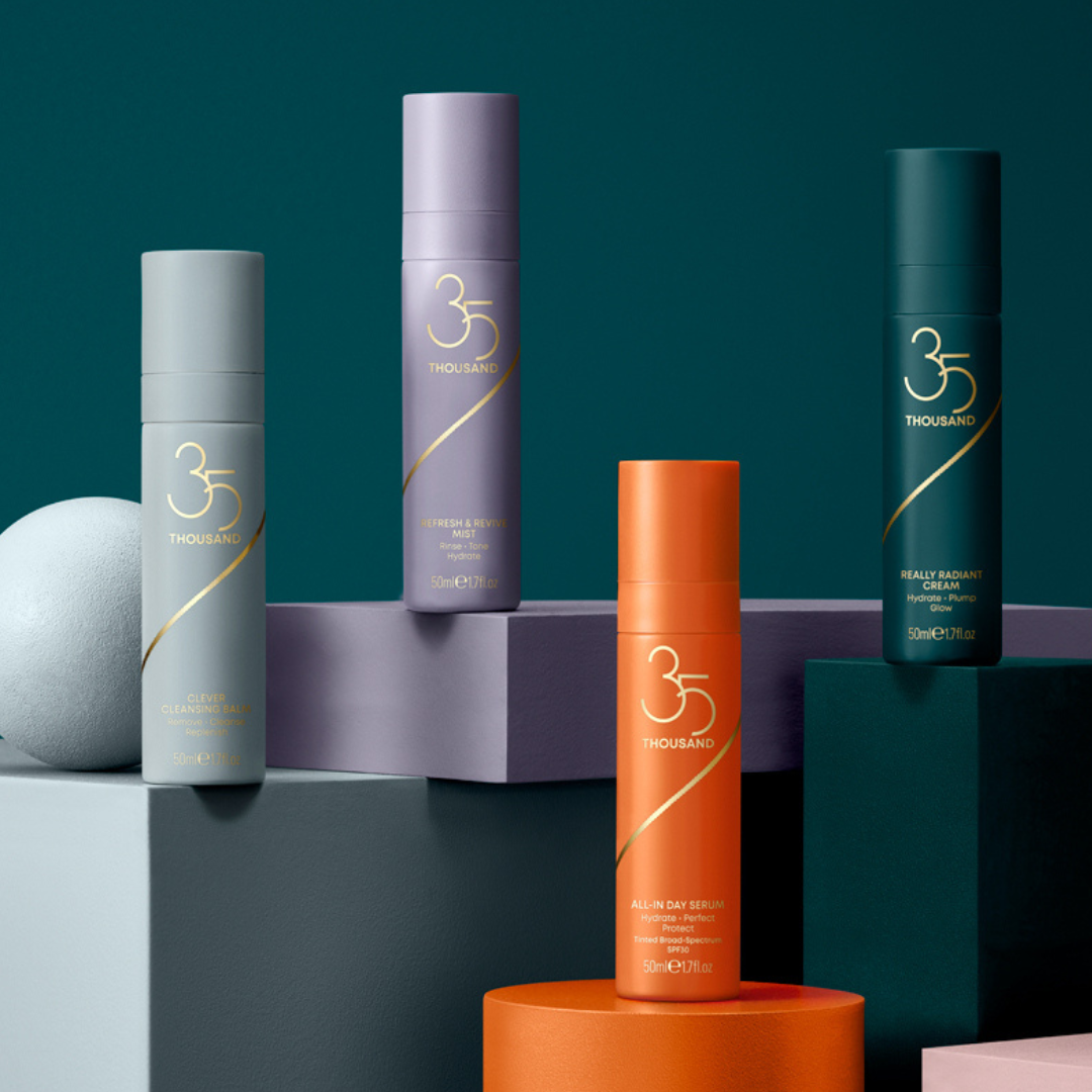 Still shot of Clever Cleansing Balm, Refresh & Revive Mist, Really Radiant Cream and All-In Day Serum with SPF 30, all sitting atop colored blocks with a teal background. 