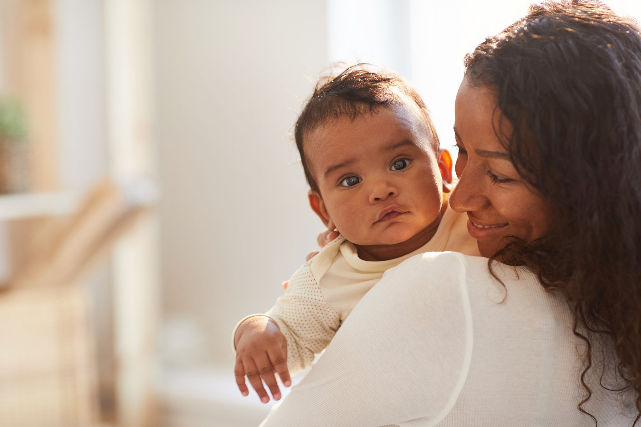 Mother smiling at baby while holding baby in her arms