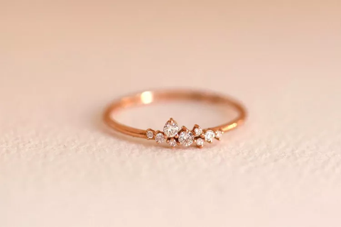 A dainty, asymmetrical engagement ring created with a cluster of diamonds and a thin band