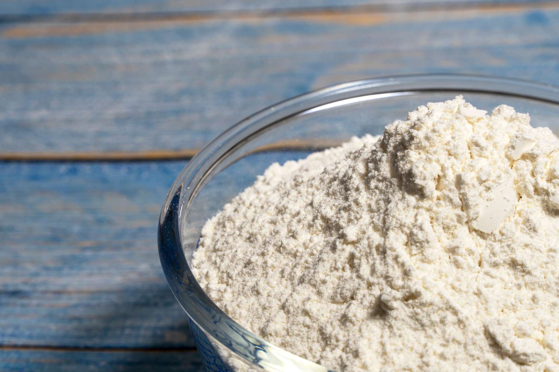 A glass bowl of flour sitting on a table