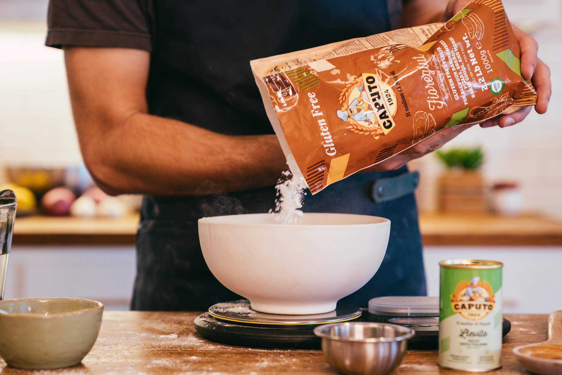 gluten-free flour being poured into a white bowl on a kitchen scale