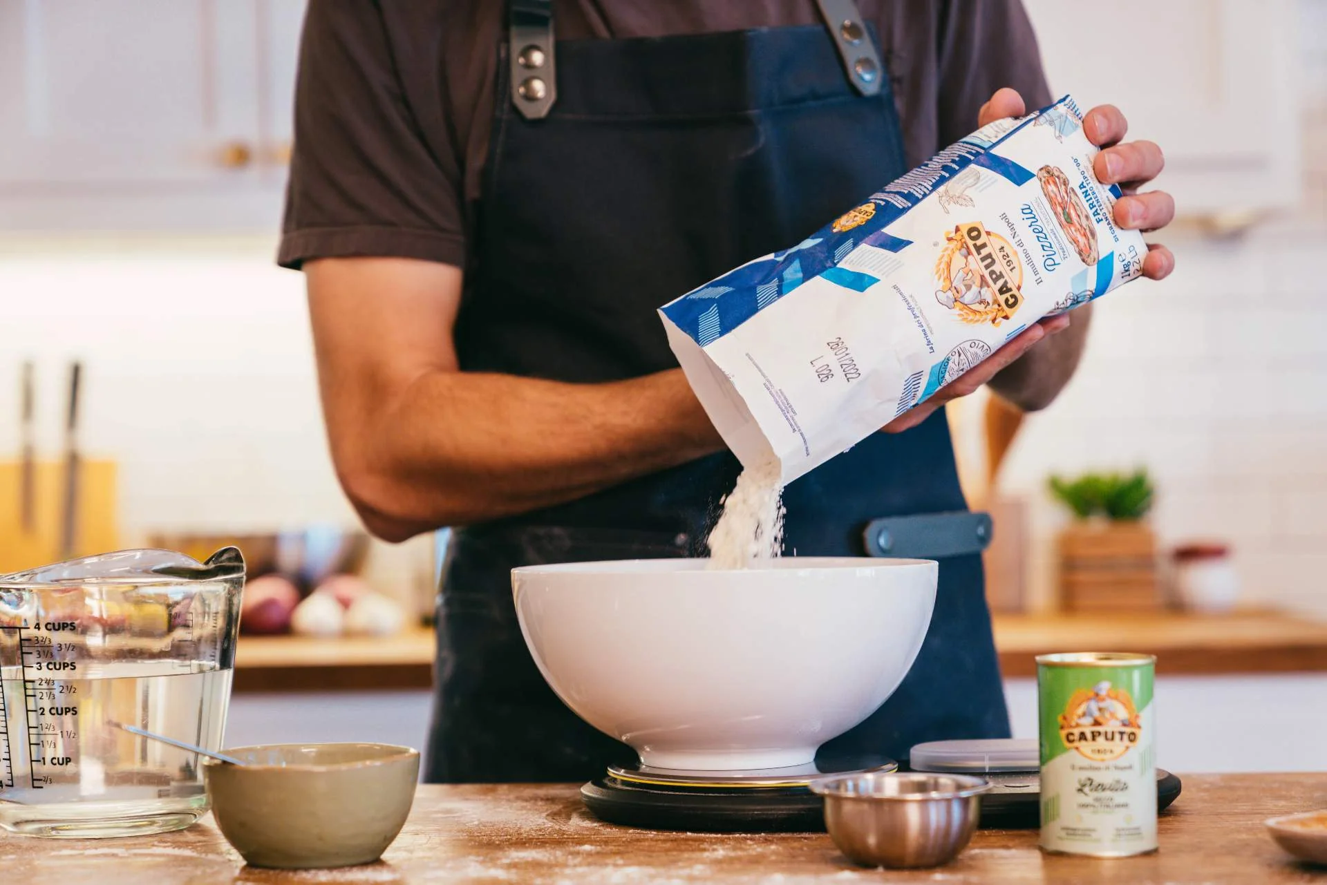 Hand pouring 00 flour into a bowl on a scale