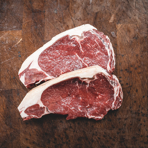 Two steaks on a rustic cutting board