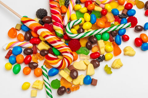 Vibrantly colored candy canes, chocolate-coated nuts, and dried fruits scattered  on the table