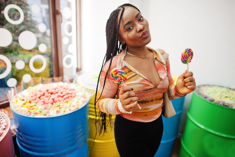 Woman holding suckers next to containers of salt water taffy.