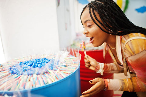 Woman looking at assorted candies in a barrel.