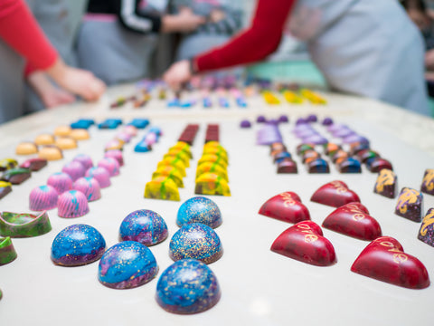 Two ladies lay their handmade candies on a pristine white table.