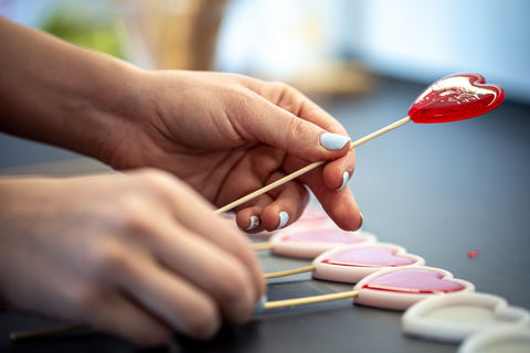 Woman making heart-shaped hard candy.