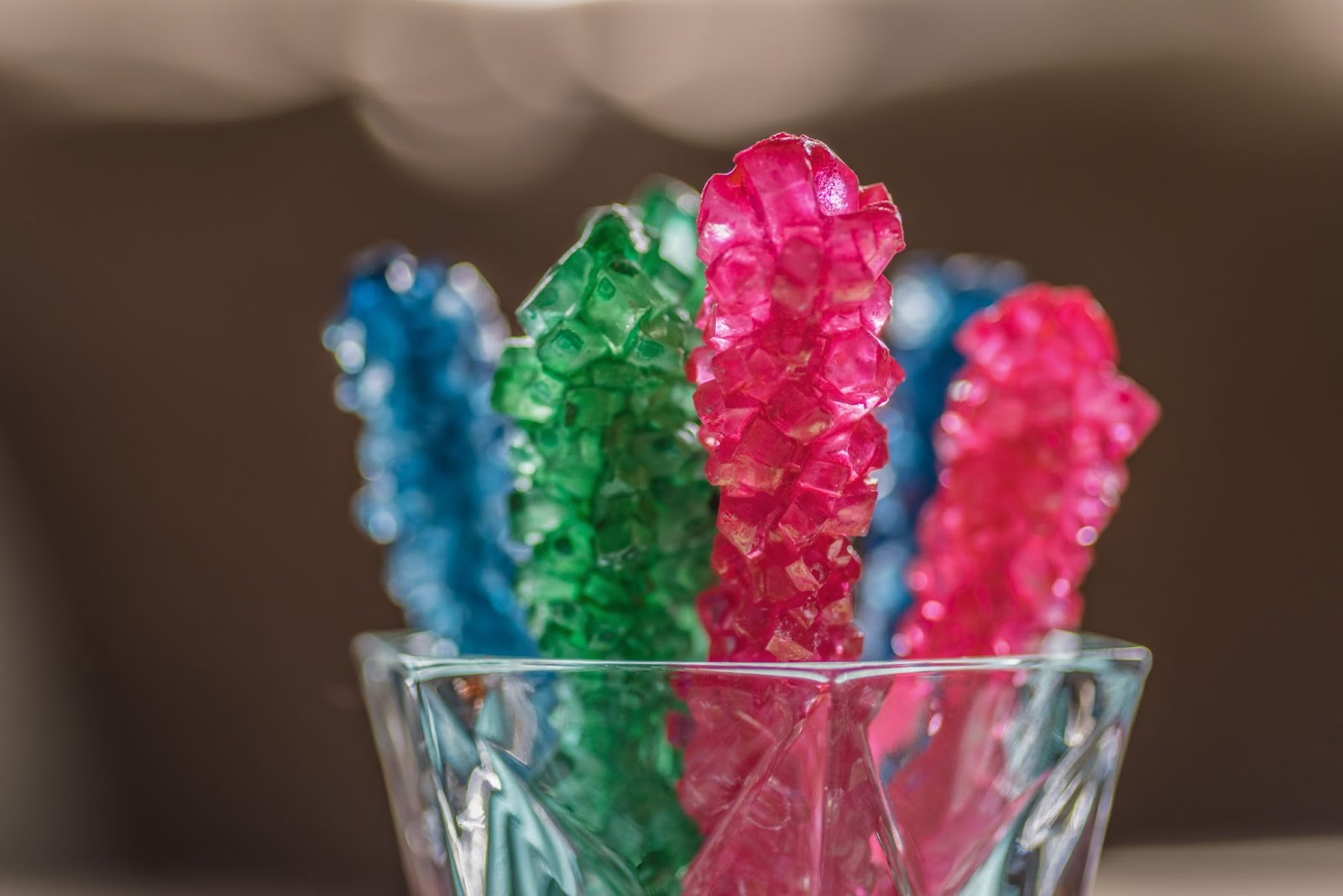 Close-up of colorful rock candy sticks in a glass.