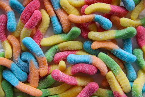 Vibrant, multi-colored gummy worms with a textured, sugar-coated surface, offering a perfect blend of sweet and sour flavors.