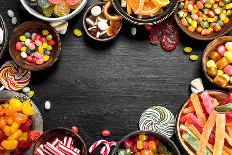 Assortment of various sweet candies, including jellies, gummies, hard candies, and more, displayed in decorative bowls.