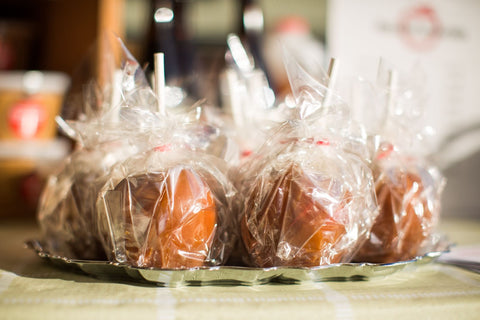 Caramel Apple Pops wrapped in plastic on a serving dish.