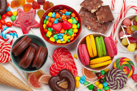 : Various candies and desserts in bowls and on a wooden surface.