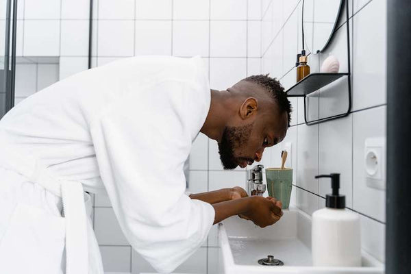 man washing his face in the sink