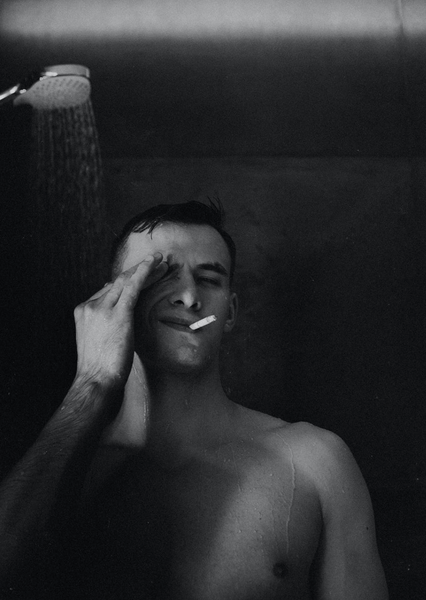 grayscale-photo-of-a-man-smoking-cigarette-while-showering