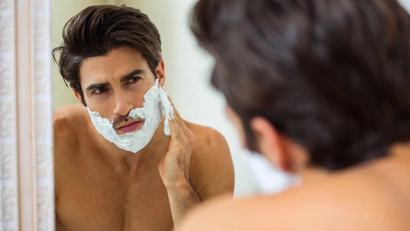 man applying shaving cream in the mirror