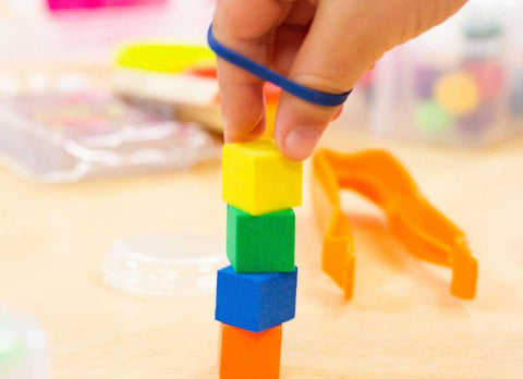 to exercise stacking blocks with rubber band around fingers