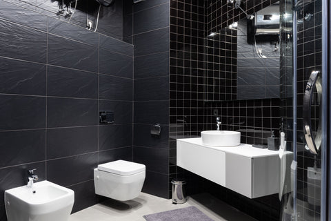 an interior of restroom decorated with black tile and a bidet