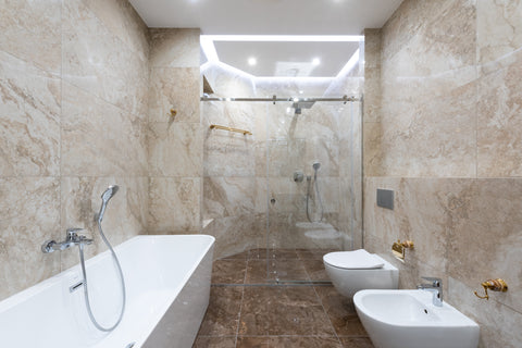 a bathtub and white sink with bidet in a modern bathroom