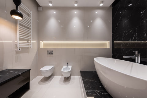 a bathroom interior with white and black tile and a bidet under hanging lights