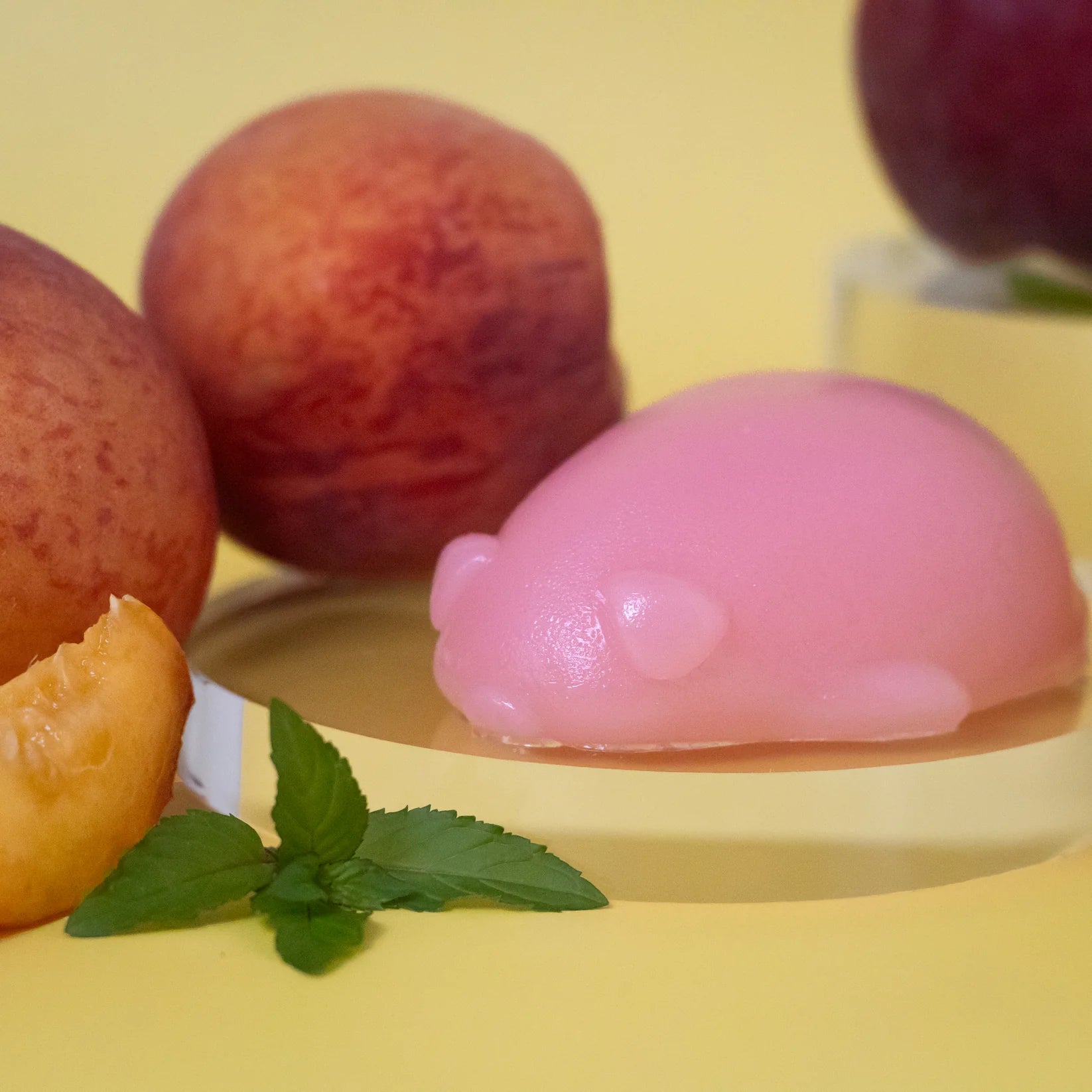 A round pink pig wiggly soap next to three peaches