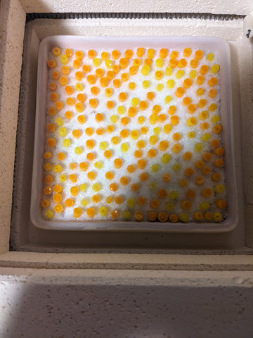 kiln with a 6x6 inch mold covered in clear frit, with murrine stuck up in it