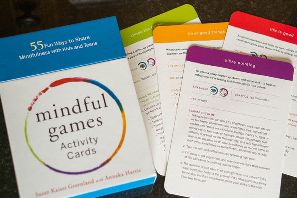 Flat lay of The Mindful Games activity cards packaging and sample cards stacked slightly off-centred 