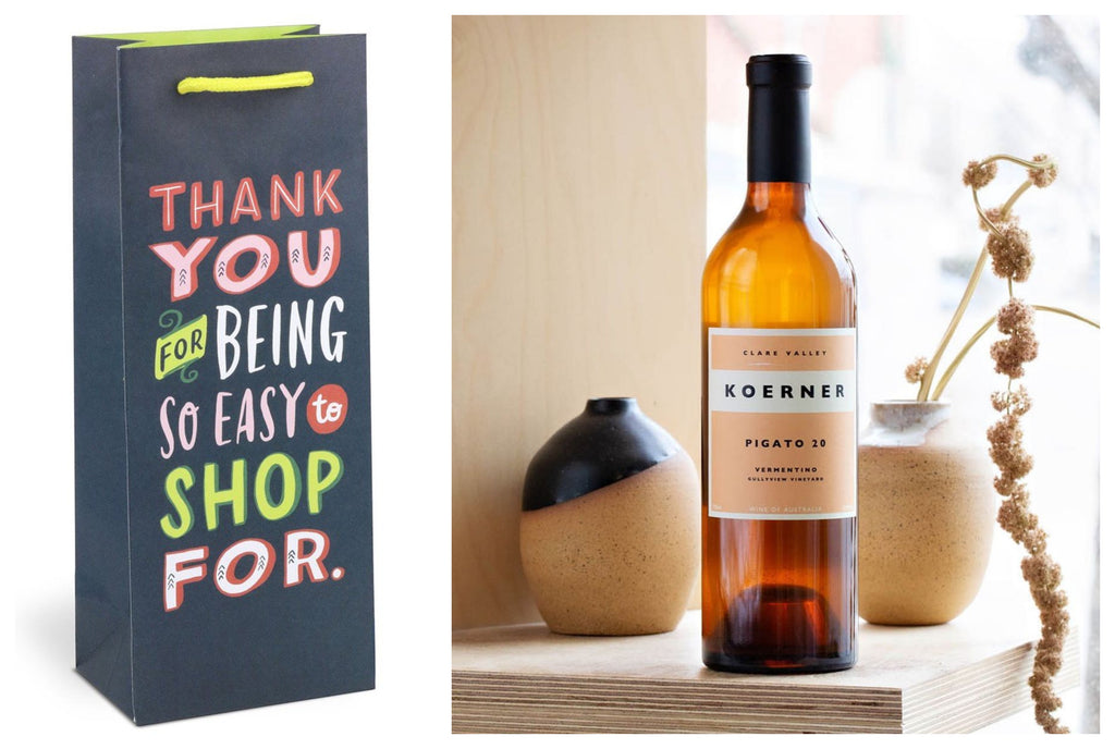 Product photo of wine gift bag that reads 'Thank you for being so easy to shop for' with a photo of a bottle of rose wine beside placed on a stone surface with botanicals in the background