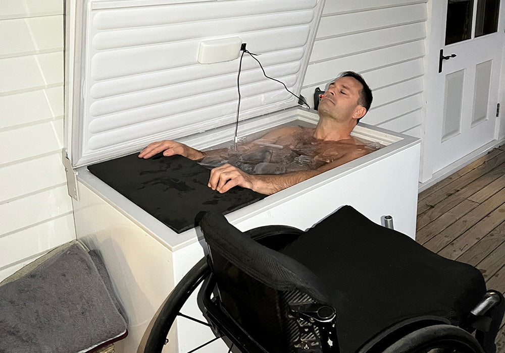Paraplegic wheelcjhair user in an ice bath cold plunge lying back eyes closed wheelchair at his side
