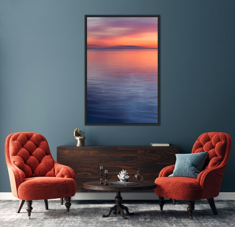 moody abstract sunset photo with orange, magenta, navy hues on blue wall with two red-orange chairs in front